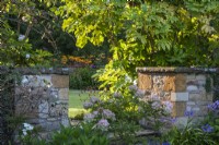 The Arts and Crafts attention to detail is seen in stone and brick pillars that frame steps at The Manor, Little Compton. Hydrangea paniculata is in the foreground with Fatsia japonica behind.