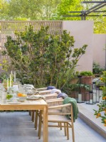 Dining area with a table and chairs. Hamptons Mediterranean Garden, Designer: Filippo Dester Garden Club London, RHS Chelsea Flower Show 2023
