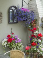 Outside seating area with hanging baskets and containers of summer bedding plants