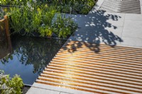 Tiled boardwalk with a fluted copper grooves with water from the water feature located above