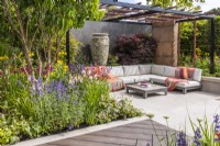 Contemporary garden with secluded seating area, steel pergola, walking board and large ceramic vase. Border planted with Acer palmatum, Heptacodium and coloured perenials. Designer: Kevin Dennis, Bord Bia Bloom 2023