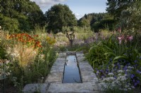 Rill and stream in summer walled garden, informal planting of drought tolerant plants in gravel