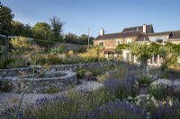 Small circular pond with stone sides in drought tolerant garden planted with Lavender, Pennisetum villosum and Fennel.  The Walled Garden at Staverton, Devon