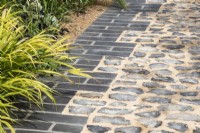 Grey brick and cobbled path with Hakonechloa macra  - designer Lucy Taylor - The Traditional Townhouse Garden -  RHS Hampton Court Palace Garden Festival.