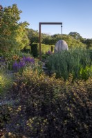 The steam bent oak 'egg' seat from Chelsea Flower Show 2021 takes centre stage in the dry garden at Holt Farm Gardens, Somerset