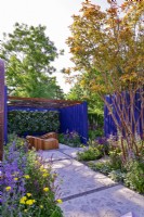 Garden space surrounded by a navy blue painted panels with path with an original leaves design and relaxation area with decorative wooden deckchairs set against living green wall under  openwork of pergola roof. Planting includes: Achillea millefolium 'Moonshine', Nepeta faassenii 'Junior Walker, Salvias nemorosa 'Caradonna Pink', 'Amethyst' and  multi-stem Lagerstroemia indica. June
Bord Bia Bloom, Dublin
Designer: Jane McCorkell
