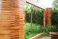Ornamental wooden arches made of red cedar in the garden, Prunus maackii Amber Beauty; Silene fimbriata 