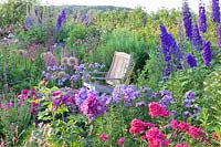 Seating area with Phlox paniculata Lilac Time, Phlox paniculata Grenadine Dream, Rosa, Delphinium Pagan Purples 