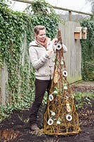 Woman decorates willow trellis with bird food 