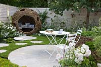 Willow arbor and terrace in a small garden with pond and running chamomile as a lawn substitute, Chamaemelum nobile 