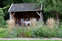 Covered seating area, in front of it reed grass and Calamagrostis acutiflora Overdam, Gaura lindheimeri Whirling Butterflies 