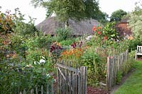 Country garden with thatched house in the background 