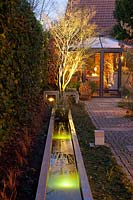 Light in the garden, illuminated water basin with pavilion in the background 