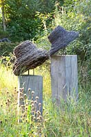 Flower meadow in late summer with hat sculptures made of willow 