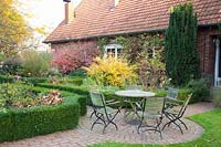 Country garden with seating area in October, Corylopsis pauciflora, Euonymus alatus 
