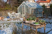 Seating area in front of greenhouse and decorated table in winter 