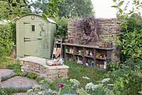 Cottage garden with tool shed and shelf made of old wooden boxes 