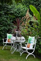 Seating area in the garden with Cordyline australis in a pot 