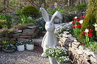 Rock garden in spring with concrete rabbit sculpture 