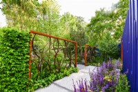Garden space with openwork corten panel with a geometric design in the center, navy blue painted panels, path with an original leaves design among dense plants. June
Bord Bia Bloom, Dublin
Designer: Jane McCorkell
