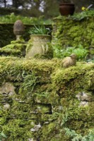 Mossy stone wall with clay bird at Cerney House Gardens in March