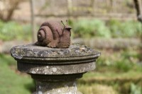 Metal snail on a sundial in March