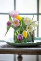 Mix of fringed tulips in a green vases on display.Small bouquet of flowers.
