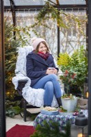 Woman sitting in greenhouse with a hot drink