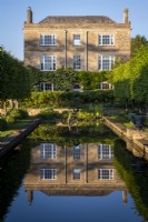 View towards Daglingworth House, Gloucestershire across the formal garden pond with a perfect reflection of the house
