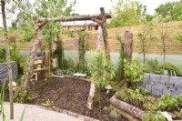 Childrens play area with swing made of raw birch trunks. Strawberry bed. Planted with Pyrus in a woodland inspired garden surrounded by a wooden planks fence. June
Designer: Mary Anne Farenden. Bord Bia Bloom, Super Garden, Dublin, Ireland.