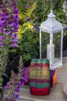 Tibetan meditation cushions and a metal lantern in a garden meditation corner surrounded by plants