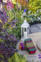 Tibetan meditation cushions and a metal lantern in a garden meditation corner among plants