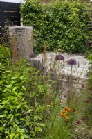 Brick filled gabions surrounded by perennials such as alliums, eremurus, and grasses in The 'Slow Burn' Garden at BBC Gardener's World Live 2015, June