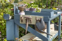 Wooden blue potting bench with garden tools and recycled cardboard cup pots, June