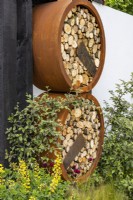 Round insect hotels made of wood and rusty rings in an urban front garden. Designer: Nicola Haines