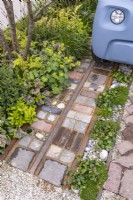Front garden - detail of driveway made with reclaimed cobbles, tiles, bricks, rusted rails, stones with low level green foliage. Designer: Nicola Haines, Citroen Power of One at Bord Bia Bloom Dublin 2023