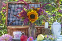 Summer bouquet with sunflowers and Amaranthus caudatus on the table set for picnic.