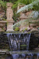 Stepped waterfalls in semi tropical garden with classical statues behind