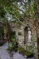 Oleander grown as trees around a walled garden room,  Classical statues sited in stone wall