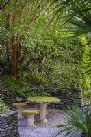 Stone tables in quiet gravel garden with bamboos and palms above