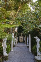 Avenue of classical statues with tall trees shading