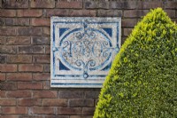 Plaque on brick wall dated 1980 with clipped pyramid of Box. April. Spring. 