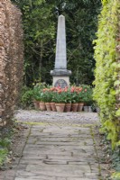 Obelisk with terracotta pots planted with tulips at base. April. Spring. 