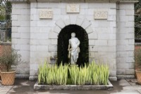 Statue in niche in the Nymphaeum. Iris in front (not in flower). April. Spring. 