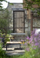Cotswold stone wall and wooden door. The Cotswold Garden, RHS Malvern Spring Festival 2024. Design: Mark Draper, Graduate Gardeners.