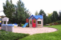 A playground for small children in a circular sandpit in summer garden.